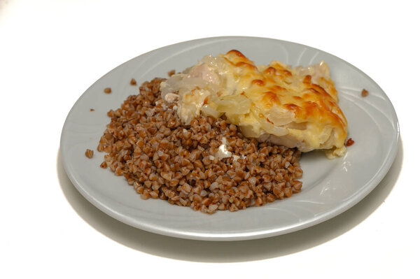 Traditional buckwheat porridge served with tender roasted meat on a clean white background.