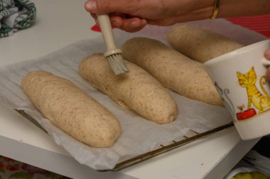 Kadın pişirmeden önce taze Graham ekmeğine yumurta yıkamayı dikkatlice uyguluyor..