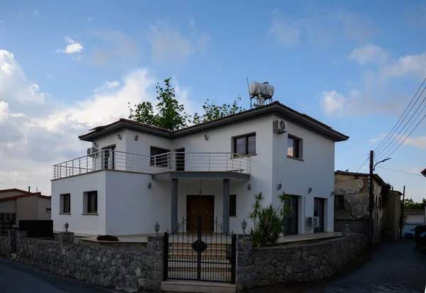 Kıbrıs 'ın güneşli bir köyünde sakin bir caddede Akdeniz tarzında büyüleyici beyaz duvarlı bir ev..