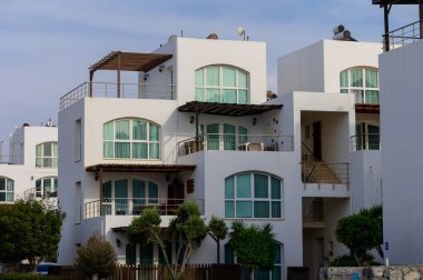 Kıbrıs 'ta sakin bir yerleşim bölgesinde Akdeniz tarzı mimarisi olan beyaz modern villalar. Güneşli hava ve açık gökyüzü.
