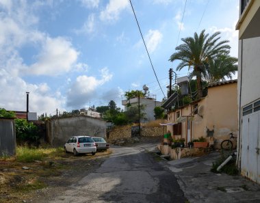 Kıbrıs 'ın tarihi Lefke kasabasında, güneşli bir günde etrafı beyazlatılmış binalar ve otantik yerel cazibeyle çevrili sessiz dar bir cadde.