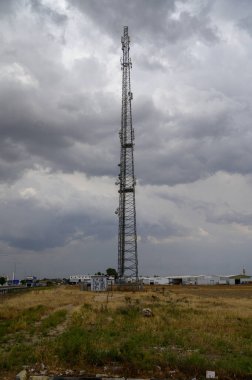 Kıbrıs 'taki telekomünikasyon anten kulesi, mavi gökyüzüne karşı dik duruyor, yakındaki bölgelere mobil ve internet sinyalleri sağlıyor.