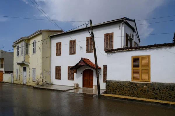 Hafif bir yağmur, taş kaldırım ve nemden parlayan beyaz duvarlar sırasındaki tipik Kıbrıs caddesi.