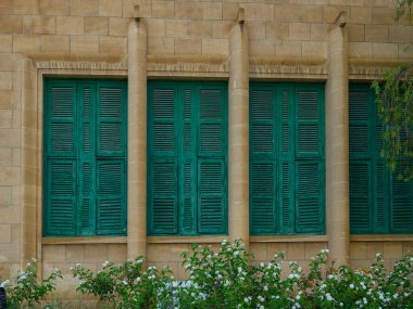 Beyazlatılmış duvarları, eski taş işçiliği ve pencerelerinde büyüleyici yeşil ahşap panjurları olan tarihi Kıbrıs evi..