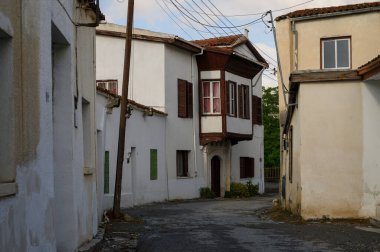 Kıbrıs 'ta geleneksel taş bir ev ve çiçeklerle dolu güzel dekore edilmiş bir balkonu olan pitoresk bir cadde..