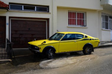 Lefke Kıbrıs 05.30.2025, Kıbrıs 'ın dar bir sokağına park edilmiş klasik sarı Mitsubishi spor arabası. Retro tasarım ve parlak renk nostaljik 1980 'leri anımsatıyor.