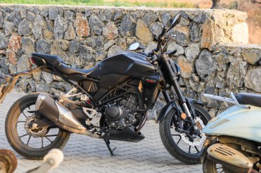 Bir evin önüne park edilmiş siyah bir motorsikletin fotoğrafı..