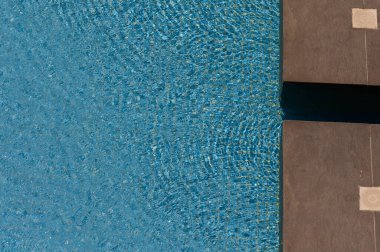 Kıbrıs 'ta güneşli bir yüzme havuzunda temiz su dokusu. Işık yansımaları ve yaz titreşimleriyle parıldayan yüzey.