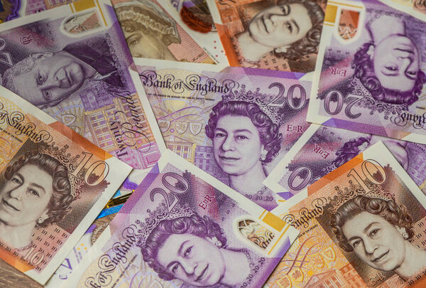 Крупный план британских банкнот весом 20 фунтов с портретами короля Карла III и королевы Елизаветы II, символа переходной валюты и монархии Великобритании.