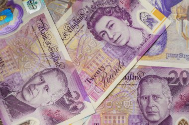 İngiliz para birimi ve monarşi geçişinin sembolü olan Kral III. Charles ve Kraliçe II. Elizabeth 'in portrelerini gösteren İngiltere' nin 20 pound 'luk banknotlarının yakın çekimi.