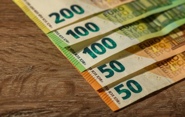 Ahşap yüzeyde sergilenen ve finans, nakit akışı ve Avrupa ekonomisini temsil eden farklı değerlere sahip Avro banknotları.