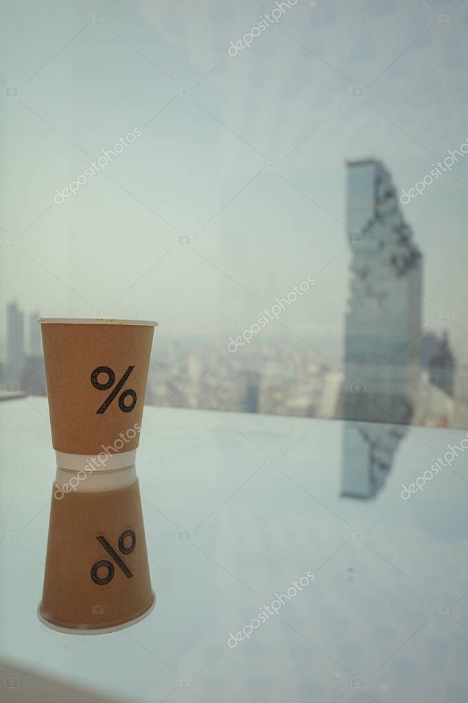 Brown coffee cup with a percent logo, city view on background