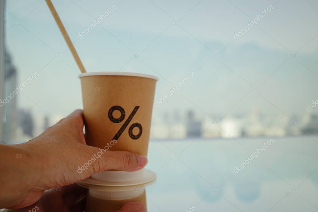 A person's hands hold brown coffee cup with a percent logo and a straw.