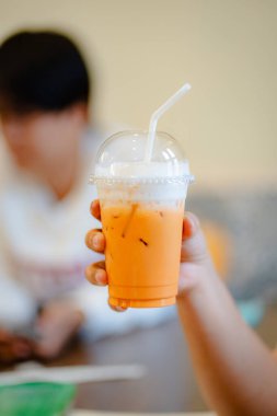 Plastik bardakta köpüklü parlak turuncu bir buzlu çay.