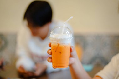 Plastik bardakta köpüklü parlak turuncu bir buzlu çay.