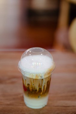 Plastik bardakta kremalı köpüklü katmanlı kahve içeceği.