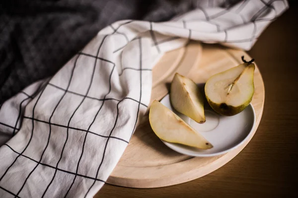 In the photo cut pear on a wooden tray and a plate.