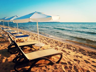 Sabah güneşin doğuşunu karşı karşıya şezlong ve deniz şemsiyelerle güzel kumlu plajı. Yaz arka planda Nessebar, Bulgaristan.