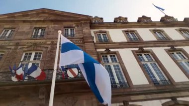 Fransa 'nın başkenti Htel de Ville de Strasbourg' un önünde Finlandiya bayrağını mavi gökyüzüne dalgalandıran rüzgar.
