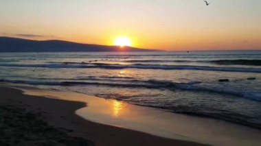 Deniz kenarında güzel gün batımı. Küçük dalgalar ve berrak gökyüzü.