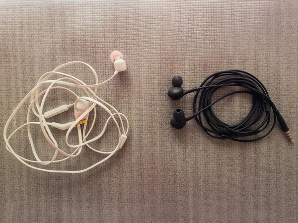 Two pairs of black and white wired headphones, for music listeni — Stock Image Two pairs of black and white wired headphones, for music listeni Stock Photo