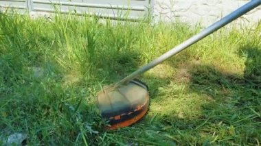 İş yerinde çim biçme makinesi. Adam özel bir ekipman kullanarak ot kesme. Bahçıvan, profesyonel bir düzeltici kullanarak çimen çimlerini biçiyor.