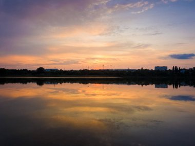 Göl yüzeyine yansıyan renkli gün batımı bulutları simetrik. 
