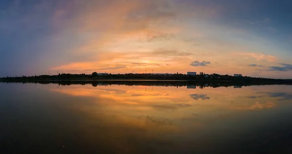 Panoramisch uitzicht op kleurrijke zonsondergang wolken symmetrisch weerspiegeld op — Stockfoto
