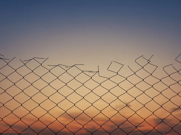 Textura de cerca de malha de arame velho contra o fundo do céu por do sol . — Fotografia de Stock