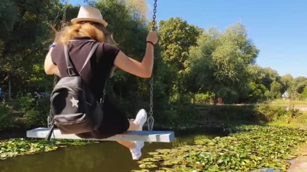 注意してください若い女性は ハスの花が咲く池の上にスイングに揺れる 休暇旅行 美しいフィットの女の子と湖で自然の背景に幸せなスイング バルダル モルドバで — ストック動画