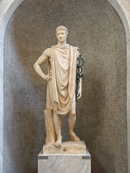 VATICAN CITY, ROME, ITALY - AUGUST 02, 2025 A classical marble statue of Hermes, known as the psychopomp holding a caduceus standing gracefully within an arched niche in the Chiaramonti Museum