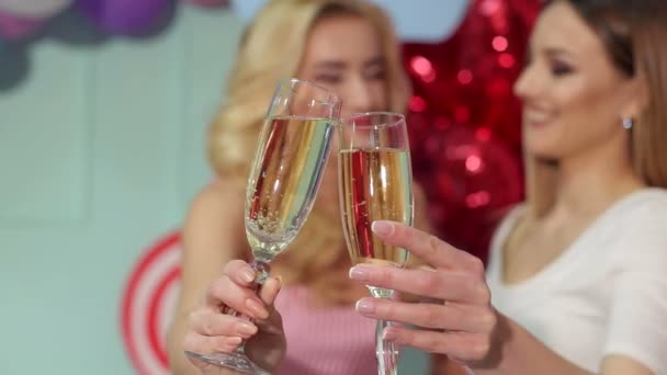 Detail ze dvou sklenkách šampaňského v rukou dvou dívek na večírku na světlé pozadí.