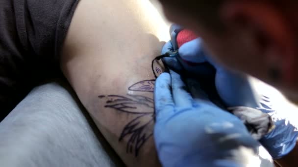 Detail člověka s modré rukavice dělá tetování na paži pro brutální muž.