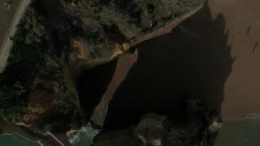 Portekiz 'in Lagos kentindeki Praia dos Estudantes Roma Köprüsü' nde ikonik bir şekilde sahile düşen güneş ışığına doğru ilerleyen insansız hava aracı. 