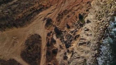 Portekiz 'in Alentejo Bölgesi' ndeki Atlantik kıyısının yanındaki kayalık araziyi gösteren insansız hava aracı kamerası kalkıyor ve yavaşça dönüyor. Güzel kıyıları ve doğası olan seyahat yerinin manzara videosu..