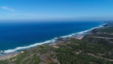 Landscape photo of beautiful green coast over Atlantic ocean in Alentejo Region, Portugal. Aerial elevated view of travel destination with beautiful coast, nature and agritourism.