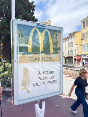 Cannes, Fransa-02.09.2025 Ziyaretçiler, Cannes 'da güneşli bir bulvar boyunca yürürler, renkli binalara hayran kalırlar ve ünlü sahil bölgesine giden belirgin bir tabela..