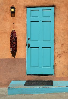 Turkuaz ahşap kapı biber ristra ve bir ev bir adobe duvara