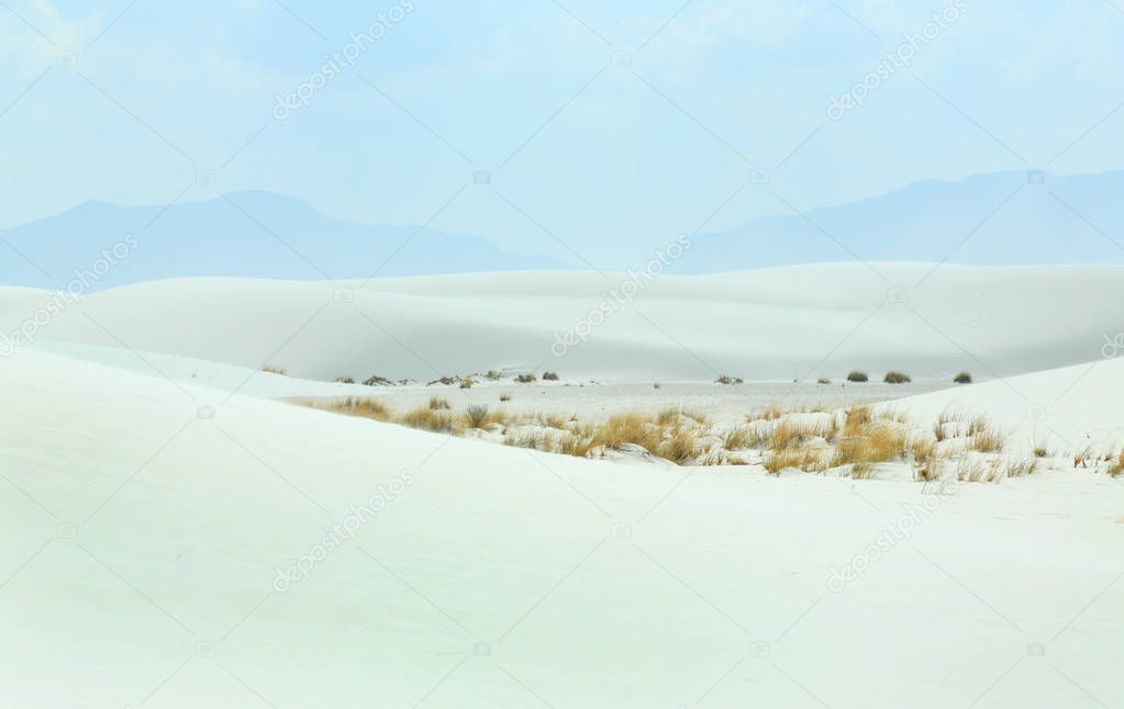 White sand dunes with wind formed ripples on a day with blue skies and clouds