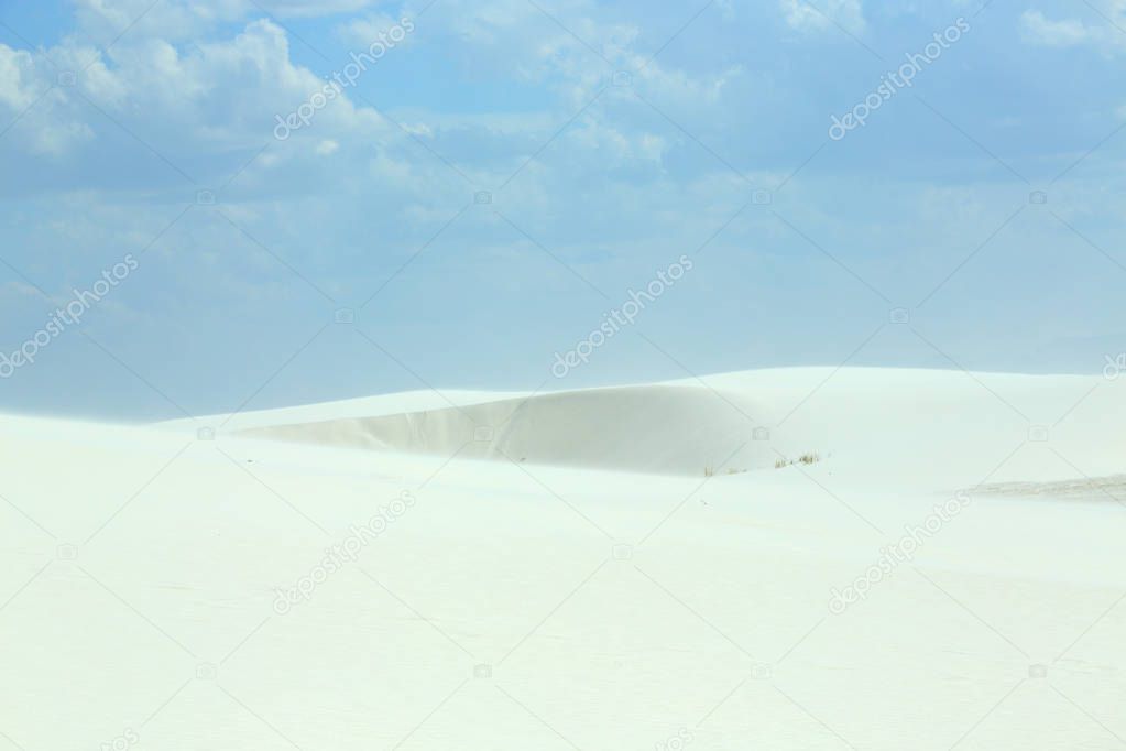 White sand dunes with wind formed ripples on a day with blue skies and clouds