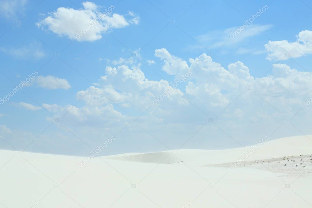 White sand dunes with wind formed ripples on a day with blue skies and clouds
