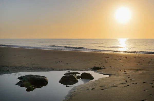 Скалы в пруду на пляже на рассвете — стоковое фото