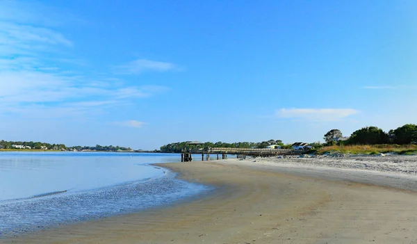 Houten pieren, bomen en huizen langs een strand — Stockfoto