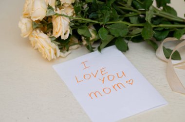 Çocuklar için el yapımı bir Anneler Günü tebrik kartı. İçinde bir buket taze sarı gül var. Aşkı, aileyi ve anneliği simgeliyor..