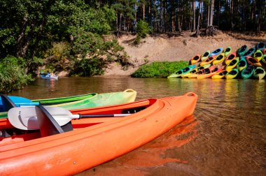 Her iki kıyıda da sayısız kano bulunan nehir kıyısı, bir kano üssünde organize edilmiş, yaz aylarında rafting macerasına, açık havaya, su sporlarına, doğa sporlarına hazırlanıyor.