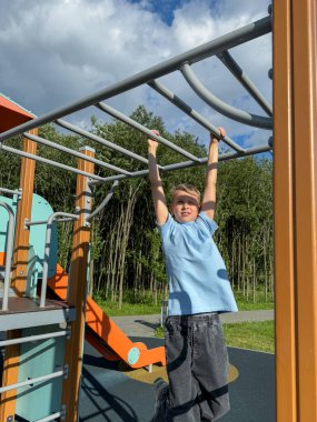 Açık hava spor parkındaki barlarda spor yapan genç bir çocuk açık bir yaz gününde spor, spor ve aktivite konsepti