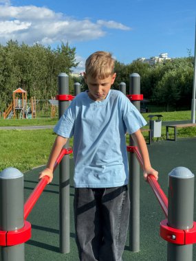 Güneşli bir yaz gününde açık hava spor parkında barlarda egzersiz yapan genç bir çocuk, spor ve spor etkinliği konsepti.