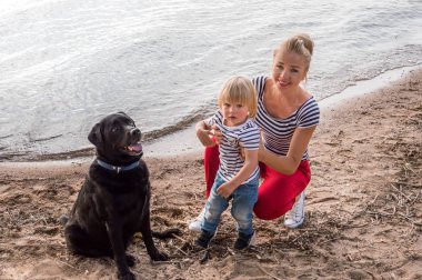 Anne ile oğlu ve sahil üzerinde oturan köpek