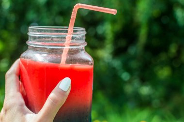 bir kadın eli açık havada bir saman ile kokteyl cam kavanozda