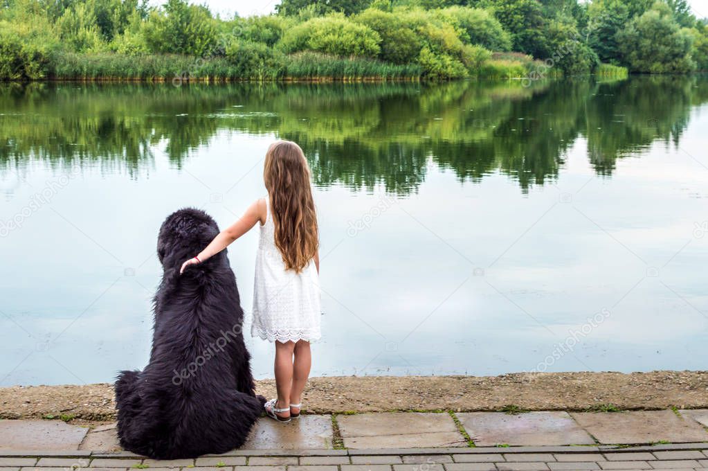 girl hugs the dog and looks at the water
